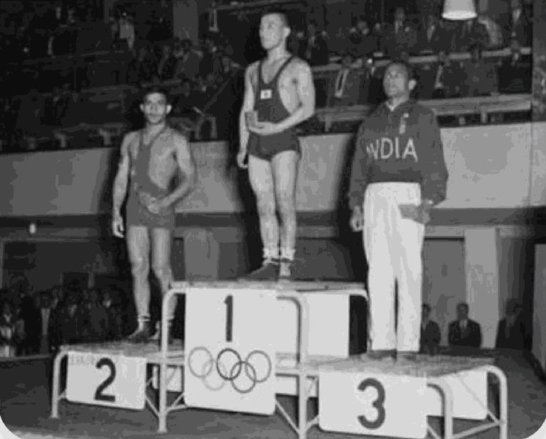 Khashaba Jadhav, in the blazer of India, standing on the third step of the Olympic podium at Helsinki 1952